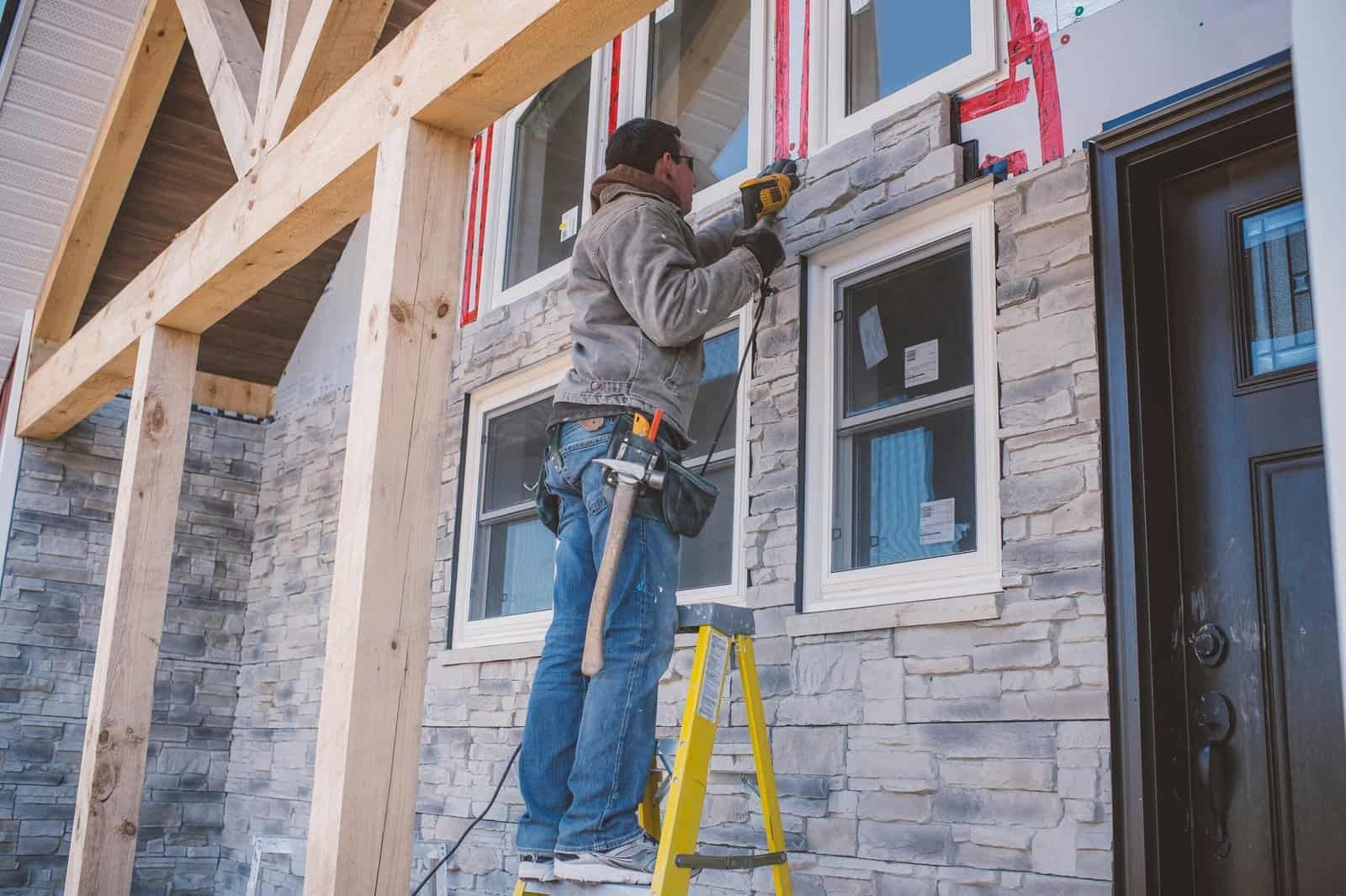 Worker installing window on a residential building under construction.