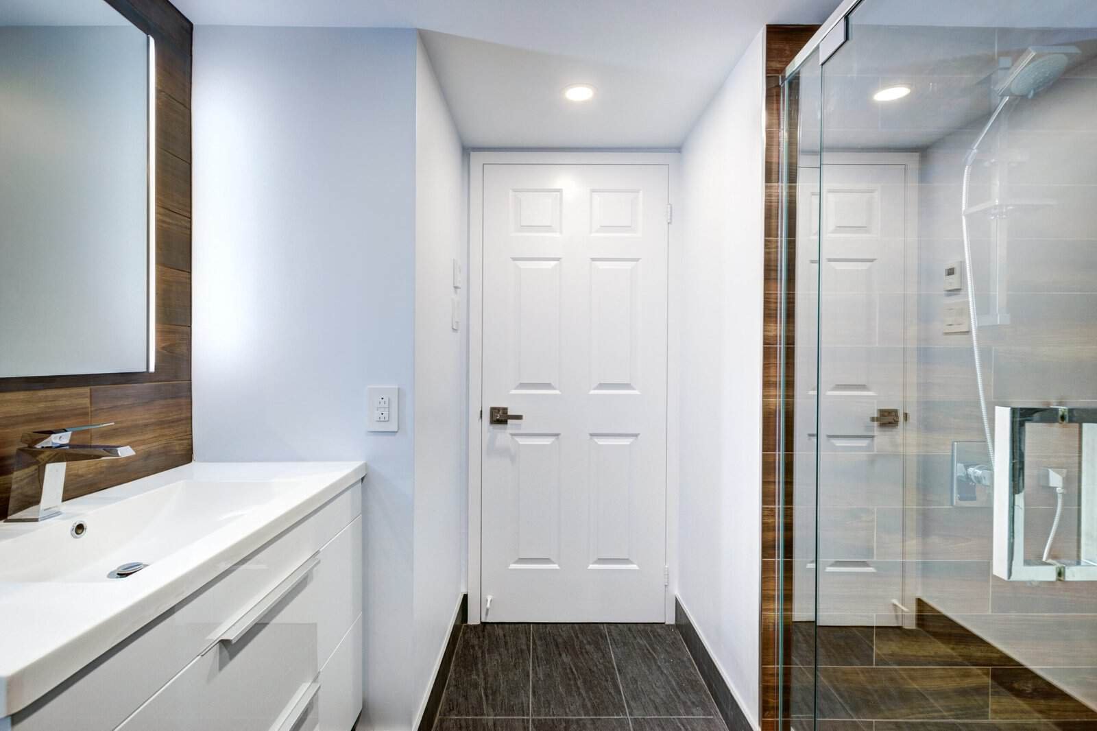 Contemporary bathroom with white vanity, glass shower, and modern fixtures.