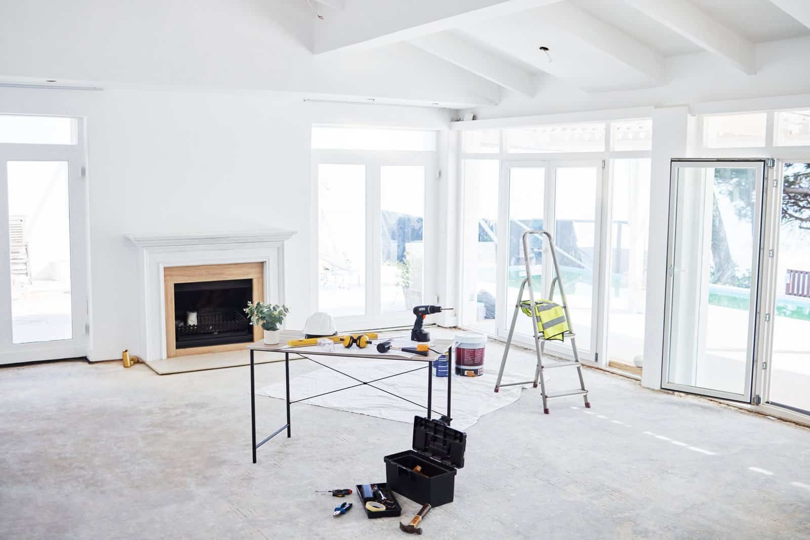 Interior construction site with tools and ladder in a bright room.