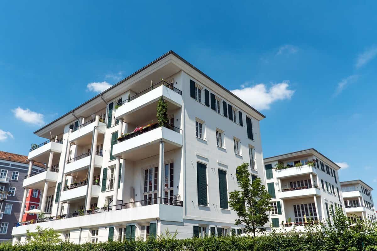 Contemporary multi-story residential building with balconies and greenery.